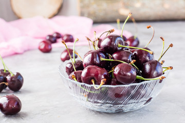 Ripe fresh sweet cherries  in a glass bowl on a gray background