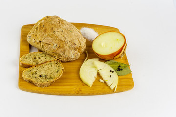Bread, onion, salt, pepper and bay leaves on a wooden board.