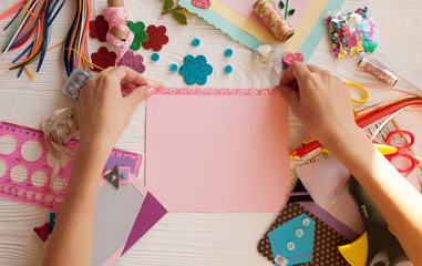 Woman's hand cut paper, scrapbooking for wedding or other festive decorations . Tools for scrapbooking.