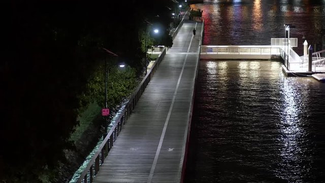 Runner and Cyclist on Clem Jones Promenade at Night on the Brisbane River
