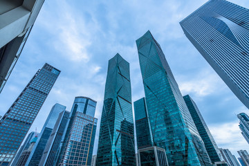 Fototapeta premium Bottom view of modern skyscrapers in business district against blue sky.