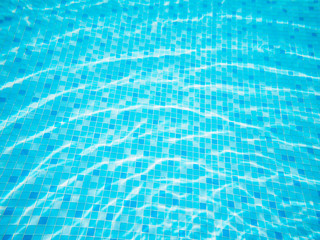 swimming pool top view background, sun reflection on the blue clear water ripples of swimming pool with mosaic bottom.