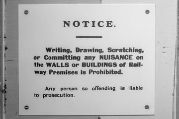 a black and white retro sign on the wall of a railway station