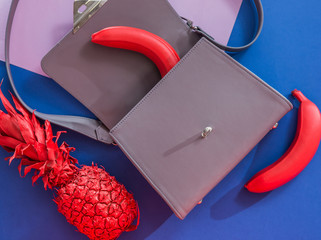 Fashion grey bag with red pineapple and bananas on the purple and dark blue background