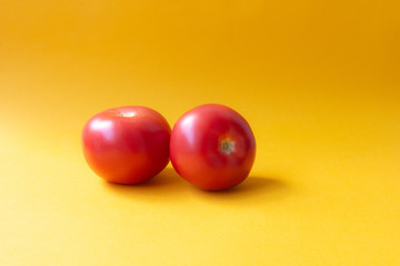 two red tomatoes on a yellow background