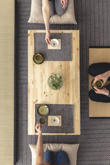 Top view on people eating japanese food on wooden desk during meeting. Real photo