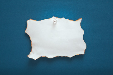 Burned edge paper pinned on blue background.