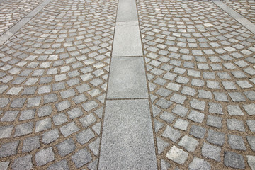New paving made with grey stone slabs and small stone cube blocks interlocked with sand in curved...