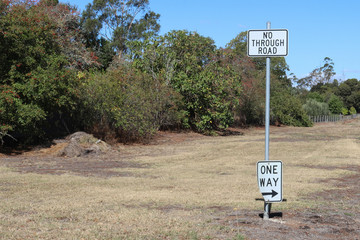 black and white No Through Road and One Way with arrow traffic signs on a metal pole