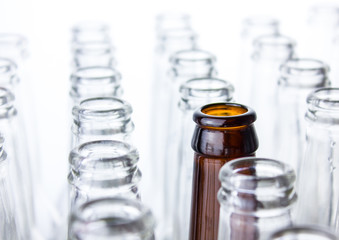 Empty clear glass bottles isolated on white background with one brown in the middle