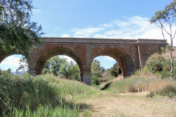 Fototapeta na wymiar HARCOURT, AUSTRALIA - February 25, 2018: the railway viaduct (1859) over Barkers Creek is constructed of Harcourt granite and comprises three main arches