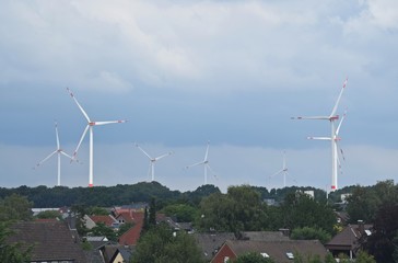 Windräder am Horizont über den Dächern einer Stadt