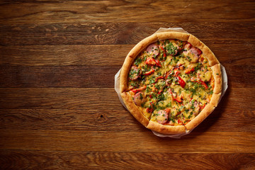 Freshly baked delicious pizza on rustic wooden background, top view, close-up, selective focus.