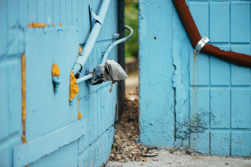 Blue wall from tiles with cyan closed hatchway and pipes close up. Background of wall of building with copy space. Two house located close.