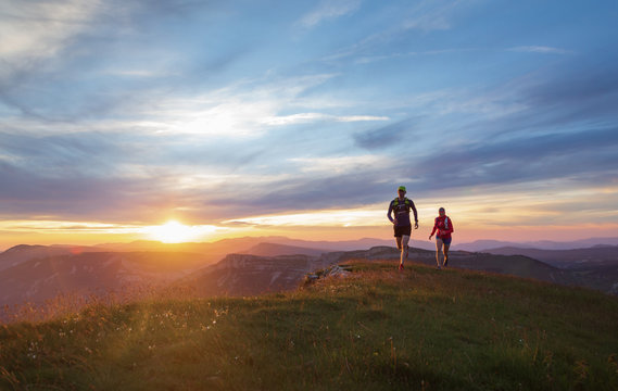 Two athletes trail running in the hills during a beautiful sunset. Shallow D.O.F.