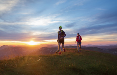 Two athletes trail running in the hills during sunset. Shallow D.O.F. and with motion blur. - obrazy, fototapety, plakaty