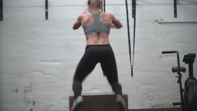 Crossfit girl making box jumps.