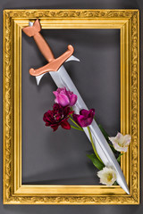 Steel sword with bronze hilt and tulip flowers in gold baguette frame. Medieval symbol of aristocracy and nobility