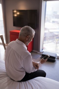 Businessman using a smart phone on bed