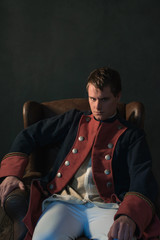 Man in empire style sitting in chair.