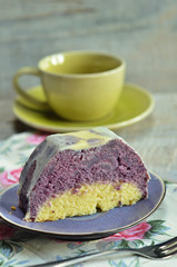 A piece of blueberry cheesecake on a plate. A green cup in the background