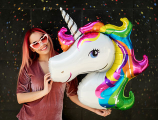 Young smiling woman holding unicorn balloon  © asashka