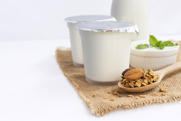 Healthy flavored yogurt in plastic cup with granola and cereal in a wooden spoon on the sackcloth with isolated on gray background. with copy space for text.