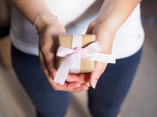Frau hält Geschenk mit rosa Schleife in ihren Händen