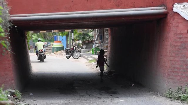 A Slow motion walk of a silhouetted child under a bridge