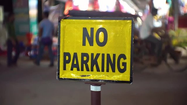 Yellow No Parking sign on a busy street