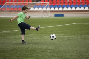 Obraz premium child run soccer (football) player. Boy with ball on green grass
