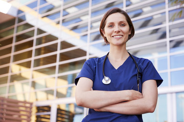 Smiling white female healthcare worker outdoors, waist up