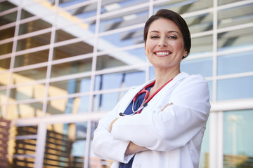 Smiling Hispanic female healthcare worker with arms crossed