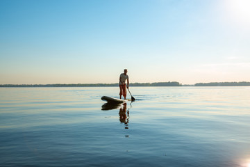 Man is training on a SUP board on a large river