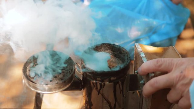 bee-maker of a smoke pipe beeper smoker device for repelling evil bees. slow motion video apiary. lifestyle beekeeping concept bee agriculture