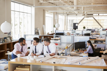Three male architects in discussion in an open plan office