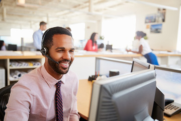 Smiling male call centre worker looking at screen, close-up