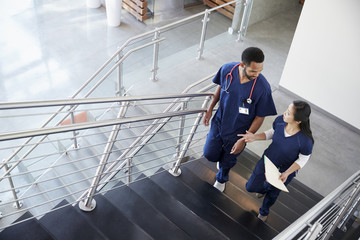 Two healthcare colleagues talking on the stairs at hospital - Powered by Adobe
