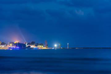 Naklejka na ściany i meble beautiful night view of the sea and the port in the illumination with the lighthouse of the city. Side, Turkey
