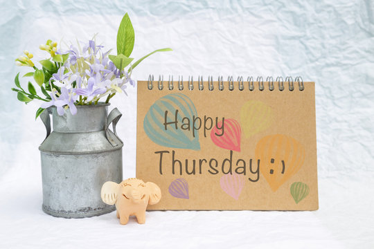 Happy thursday on design notebook cover with smiling elephant clay and tin flower pot on blurred background