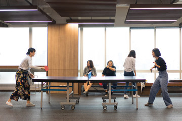 Girls is playing table tennis at the office.