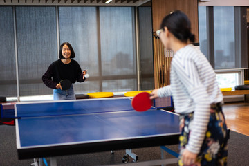 Girls is playing table tennis at the office.