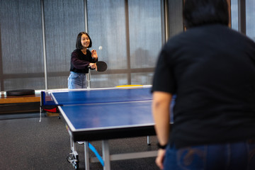 Girls is playing table tennis at the office.