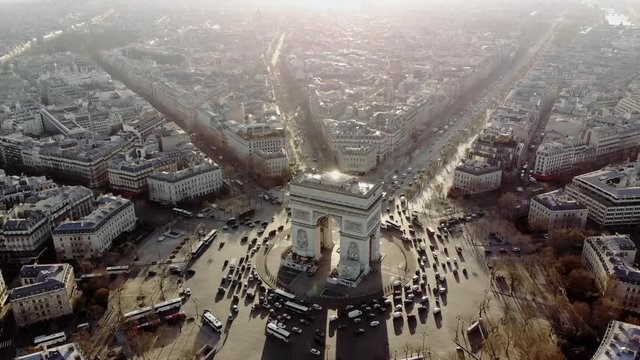 Aerial shot of the Arc de Triomphe and the traffic around it. Cars drive on the Champs Elysees. Paris in morning light.