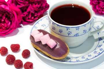 Tea time with blueberry eclair and raspberry, interesting design with pink rose. Bakery with flowers.