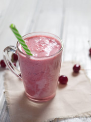 Milkshake or cherry smoothie on white wooden table. Wholesome breakfast