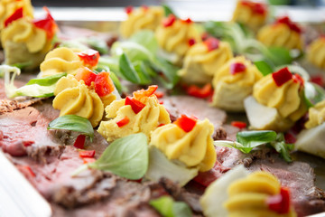 Close up photo of sliced smoked beef decorated with yellow mustard paste served on a large tray, deli platter