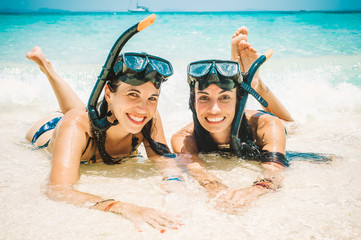 Two happy girlfriends with snorkeling mask enjoying on the beach - obrazy, fototapety, plakaty