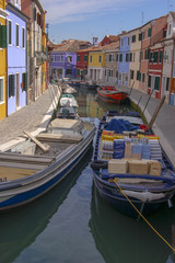 Fototapeta na wymiar Colourful houses and bustling and busy canals on the fishing village of Burano in the Venice Lagoon, Italy