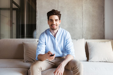 Smiling young man holding TV remote